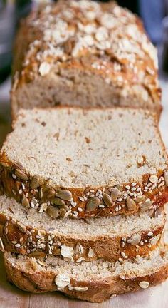 three slices of bread on a cutting board with sesame seeds and sunflower seeds all over them