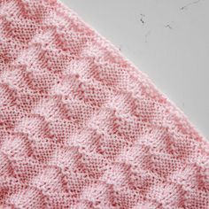 a pink knitted blanket sitting on top of a table