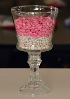 a glass filled with lots of pink and white candies on top of a table