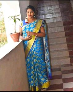 a woman in a blue and yellow sari standing on some stairs with a potted plant