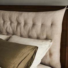 a close up of a bed with two pillows on top of it's headboard