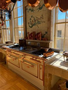 a kitchen with many pots and pans hanging from the ceiling over the stove top