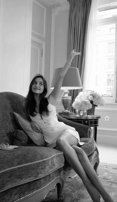 a woman sitting on top of a couch next to a lamp