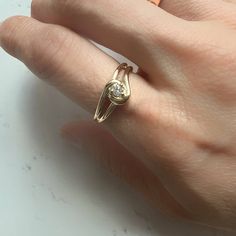 a woman's hand with a gold ring on it and a diamond in the middle