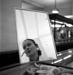 a woman sitting at a counter in front of a mirror with her reflection on it