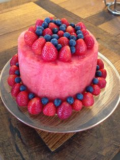 a strawberry cake with blueberries and raspberries on top is sitting on a plate