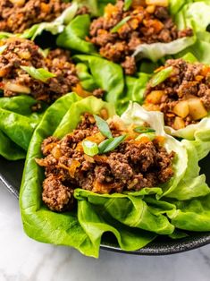 lettuce wraps filled with meat and vegetables on a marble counter top, ready to be eaten