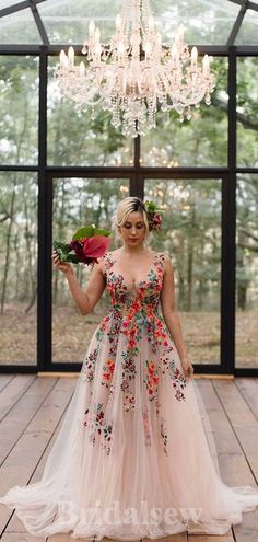 a woman standing in front of a chandelier holding flowers