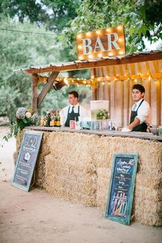 two men standing at a bar with hay bales