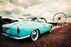 an old blue car parked next to a ferris wheel