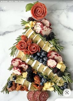 a christmas tree made out of cheese, berries and other foods on a marble table