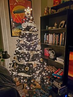 a decorated christmas tree in the corner of a living room next to a book shelf