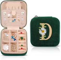 an open green case with jewelry in it and a flower on the inside is shown