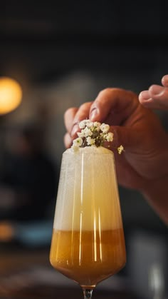 a person holding a drink with flowers on the rim in front of their face and hands