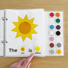 a hand pointing at an open book with the words the sun is yellow on it