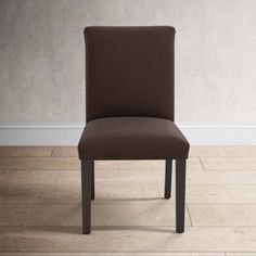 a brown chair sitting on top of a hard wood floor next to a white wall