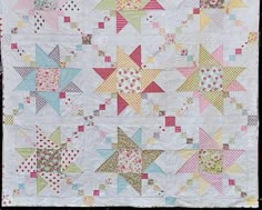 a quilted wall hanging with many different colored stars on the front and back of it