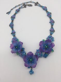 Violet Poppy Necklace Handmade by Vintage Jewelry Designer Colleen Toland Poppy necklace in pretty colors of deep purple and and soft turquoise make this necklace a stand out. There are 3 large poppy flowers along with clusters of smaller flowers and pretty blue beaded bawl bawl drops. The necklace part is constructed with tiny purple flowers in a diamond pattern, that is original to Colleen Toland and a signature design element on many of her pieces. Matching earrings are listed below. This is Blue Bohemian Necklace With Flower Charm, Bohemian Blue Flower Necklace, Blue Bohemian Flower Beaded Necklaces, Purple Whimsical Necklace For Party, Whimsical Purple Necklace For Party, Blue Flower-shaped Bohemian Necklace, Blue Bohemian Flower Necklace, Bohemian Blue Jewelry With Handmade Flowers, Handmade Purple Beaded Necklace For Weddings