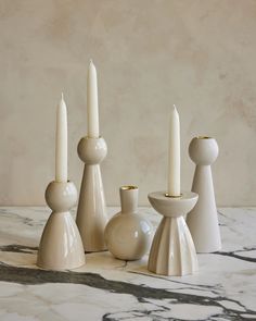 three candles are sitting next to each other on a marble counter top, with one candle in the middle