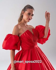 a woman in a red dress posing for the camera with her hand on her hip