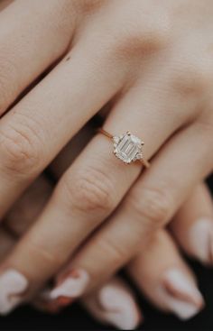 a woman's hand with a diamond ring on top of her finger and nails