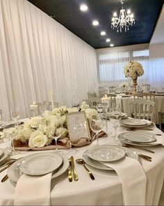 the table is set with white flowers and silverware for an elegant dinner party or reception