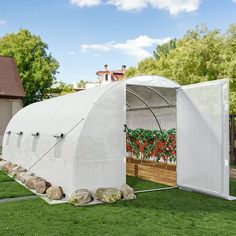 a large white greenhouse sitting on top of a lush green field