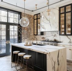 an elegant kitchen with marble counter tops and black cabinetry, along with two bar stools