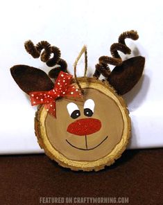 a piece of wood with a reindeer face on it and a red bow around its head