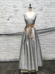 Luxury Silk Tea Length Dress For Evening, Luxury Dresses With Satin Finish And Silk Lining, Luxury Taffeta Gown With Satin Finish, Luxury Chic Silk Tea Length Dress, Luxury Silk Dresses With Box Pleat, Luxury Silk Dress With Box Pleat, Luxury Sleeveless Elegant Vintage Dress, Traditional Luxury Slub Silk Dresses, Luxury Traditional Slub Silk Dresses