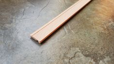 a piece of wood sitting on top of a stone floor next to a knife blade