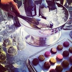 champagne being poured into a bowl with chocolates and cookies in front of wine bottles