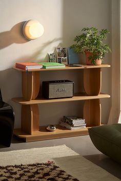 a wooden shelf with books on it next to a chair and potted plant in the corner