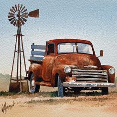 an old truck parked next to a windmill