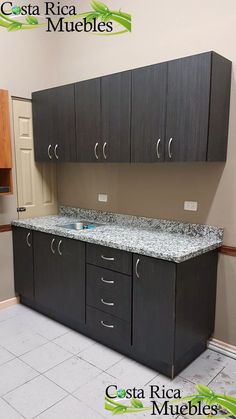 an empty kitchen with black cabinets and granite counter tops on the island in front of it