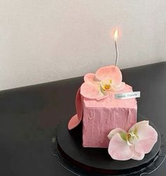 a pink cake decorated with flowers and a candle