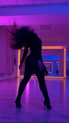 a woman is dancing on the dance floor with her hair blowing in the wind while wearing high heels