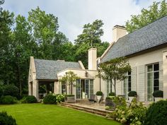 a large house with lots of windows and plants in the front yard, surrounded by lush green grass