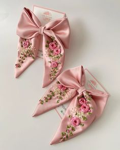 two pink bows with flowers on them sitting next to each other