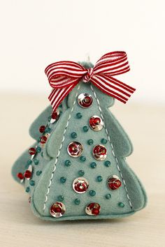 a small green christmas tree with red and white bows on it's head sitting on a table