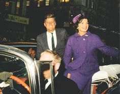 a man and woman standing next to each other in front of a car