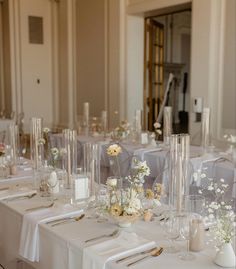 the tables are set with clear vases and white flowers