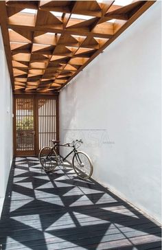 a bicycle is parked on the floor in front of a white wall and wooden slatted ceiling