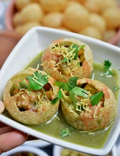 some food is in a white bowl with green sauce and garnish on top