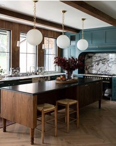 a large kitchen with blue cabinets and wooden flooring, along with marble counter tops