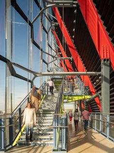 people are walking up and down the stairs in an office building with large windows on both sides