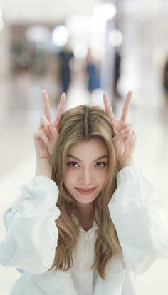 a woman with long hair holding her hands up in the air and smiling at the camera