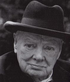 an old man with a hat and tie is looking at the camera while wearing a suit