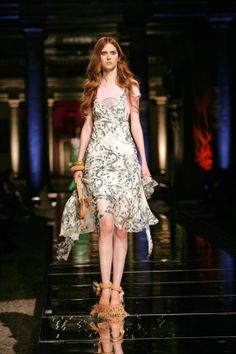 a woman walking down a runway in a dress