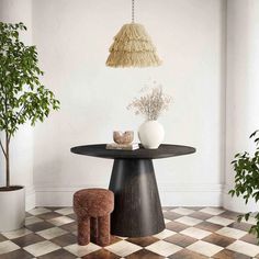 a table with two vases on it next to a potted plant in the corner